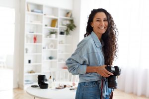 Female Photographer Posing Holding Photocamera Standing In Modern Studio