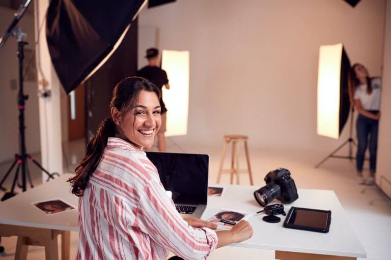 Portrait Of Professional Female Photographer Working In Studio With Assistants